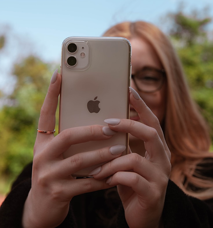A young person taking a photo with a phone outdoors